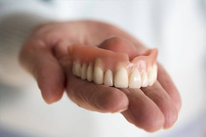 a hand holding upper dentures