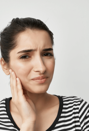 Woman holding the side of her face portraying jaw stiffness and TMJ problems